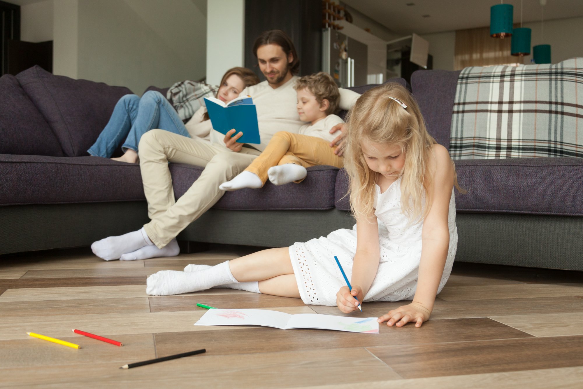 daughter-playing-floor-while-parents-son-reading-book.jpg