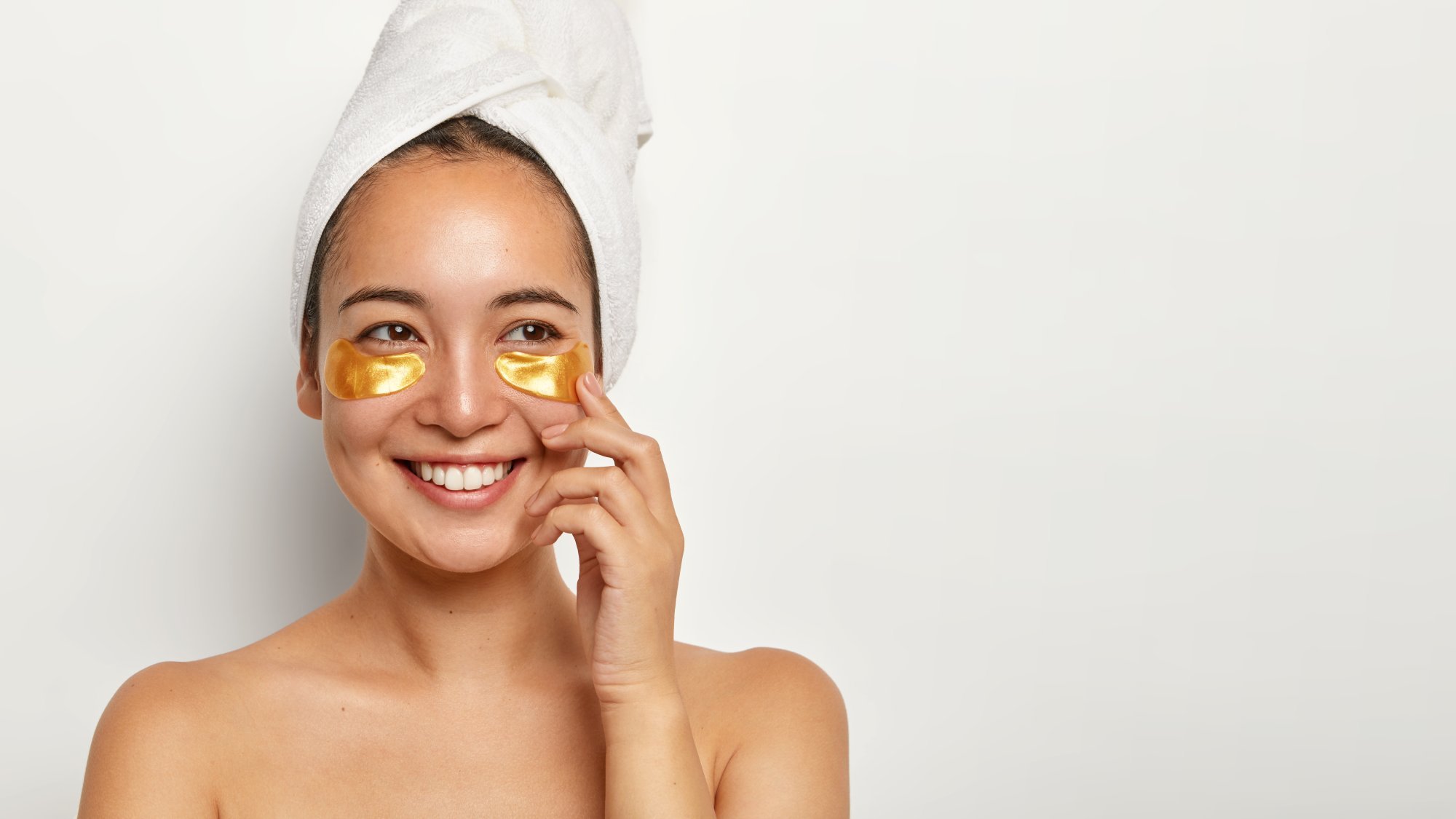 beautiful-charming-woman-with-healthy-skin-applies-cosmetic-patches-eyes-looks-gladfully-aside-thinks-about-something-pleasant-wears-wrapped-towel-head-has-spa-procedures-home.jpg